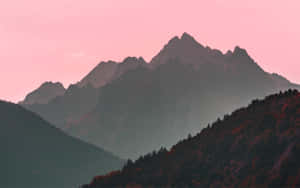 粉紅色日落映照山脈，前景是秋色樹木