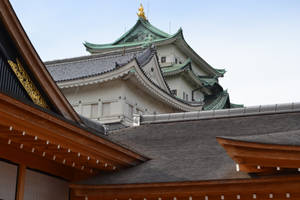 傳統日本城堡，綠色屋頂和金色細節，在淡色天空下。