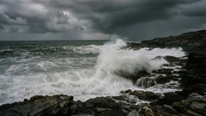 在暴風雨的天空下，海浪拍打著黑暗的岩石海岸
