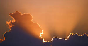 夕陽的光芒穿過烏雲，將金色光輝灑滿天空。 — 太陽 壁紙