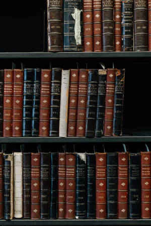 一排排古董法律書籍，深色皮革書脊上帶有金色文字，排列在木書架上。