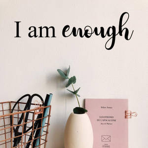 牆上有「I am enough」文字、尤加利葉花瓶、粉紅色書本和銅籃。