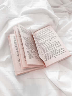 白色布料上帶有粉紅色書頁的打開書本，供閱讀用