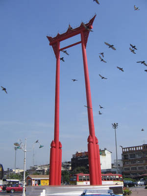 紅色巨型鞦韆紀念碑，鳥兒在城市環境中飛翔。