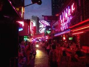 霓虹燈照亮街道，人們在夜間用餐和散步，充滿活力的城市環境。