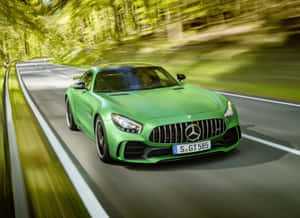 綠色 Mercedes-AMG GT S 在森林道路上飛馳，帶有模糊的動態效果。