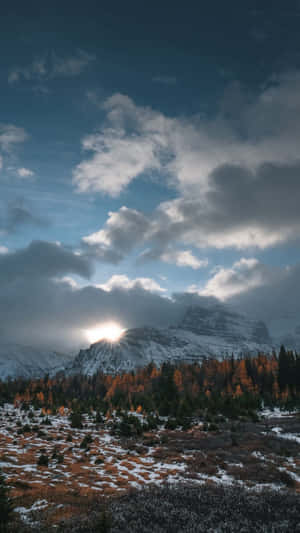 陽光穿透雲層，照耀在雪山和秋林上。