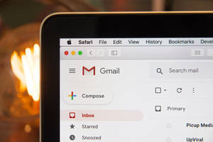 手提電腦屏幕顯示 Gmail 應用程式，背景有一個發光燈泡。