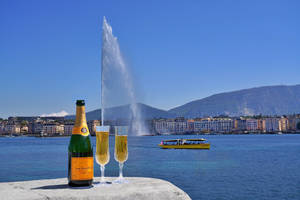 石檯上的香檳瓶和酒杯，Jet d'Eau 噴泉和湖景。