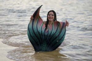 穿著彩虹美人魚尾巴的女性站在夕陽下的海中 — 美人魚 GIF 壁紙