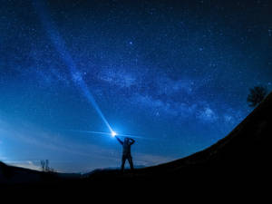 人從山丘將手電筒照向星空 — 月光 壁紙