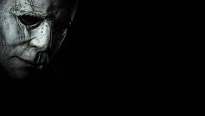 Michael Myers 戴著面具的臉在陰暗的黑暗中。