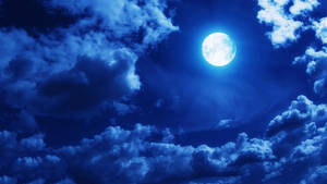 滿月在夜間透過深藍色雲層閃耀。