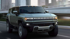 橄欖綠色Hummer EV SUV在城市高速公路上行駛，建築物模糊。