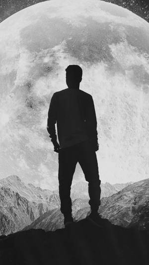 人站在山頂仰望夜空中巨大的月亮