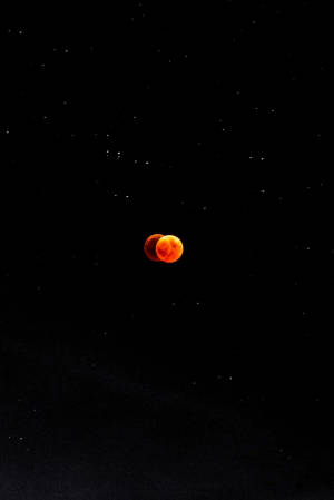 月食期間的血月在繁星點點的夜空中發出橙色光芒 — 唯美月亮動圖 壁紙
