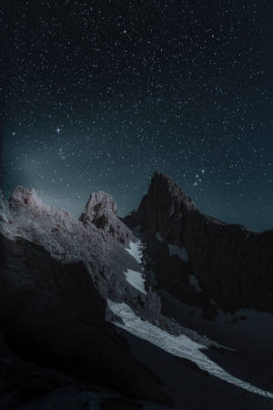 繁星點點的夜空下的積雪山峰 — 深色iPhone壁紙