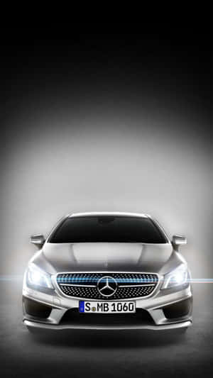 銀色 Mercedes-Benz CLA 的前視圖，頭燈亮起，格柵帶有藍色點綴。