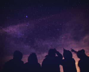一群人剪影在星空下觀看銀河系。