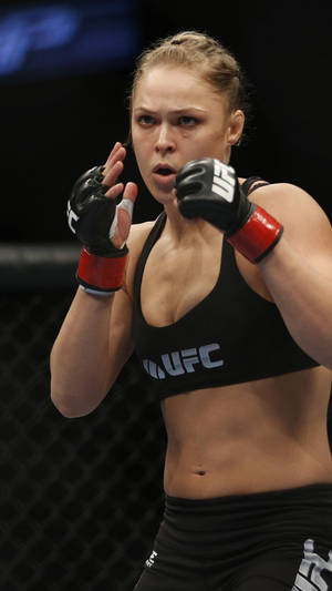女性MMA拳手穿著黑色UFC裝備在八角籠中出拳。