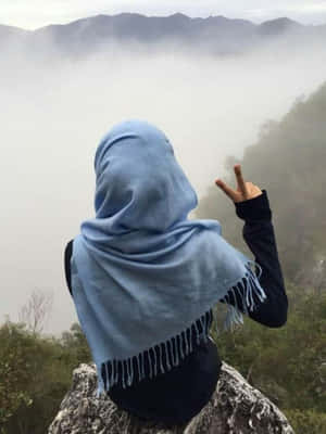 藍色頭巾人士在山崖上做出和平手勢，下方是霧谷 — 自然風景 壁紙