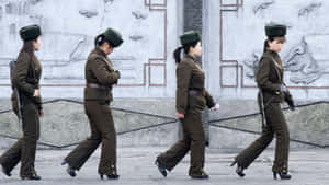 四名身穿制服的女兵在戶外排成一線行進。 — 韓國 壁紙
