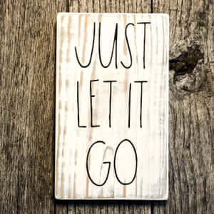 一塊木牌，上面寫有「Just Let It Go」字樣，背景為質樸的木紋。 — 語錄 壁紙