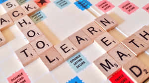 Scrabble 字母牌在遊戲板上拼出 school to learn math。 — Studio Display 壁紙