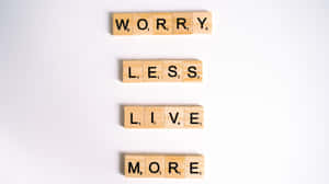 木製 Scrabble 字塊垂直排列，拼出 worry less live more。