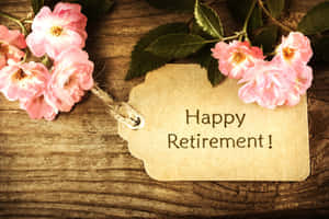 一個紙標籤，上面寫著「Happy Retirement!」，用粉紅玫瑰裝飾在木頭上。