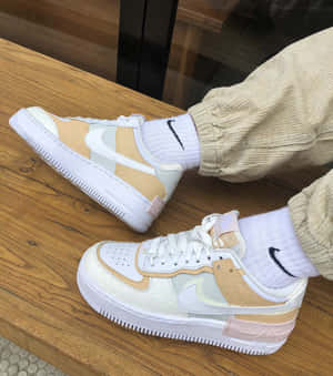 木長凳上的粉米色和白色Nike Air Force 1運動鞋，配白色襪子和米色燈芯絨褲。 — Galaxy Z Flip 8 壁紙