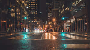 雨夜中濕滑的城市街道，閃爍的燈光在濕漉漉的路面上反射。 — 夜景城市 壁紙
