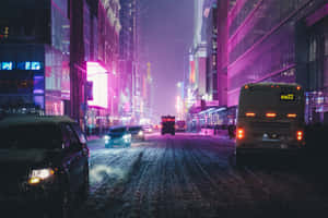 夜間積雪的城市街道，被鮮豔的霓虹招牌和車輛頭燈照亮。 — 夜景城市 壁紙