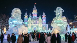 人們在飄雪中欣賞冬季節日中的巨型發光冰雕和城堡。
