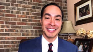穿西裝的男子在辦公室微笑，背景是磚牆和有框照片。 — 政治 壁紙