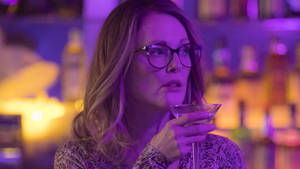 戴眼鏡的女性在紫色燈光的酒吧中手持馬提尼酒杯。 — 電影 壁紙