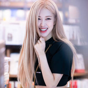一位穿著黑色上衣的金髮女性在書店裡微笑著撥弄頭髮。