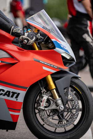 紅色Ducati Panigale V4 R電單車，騎手戴手套的手放在車把上。