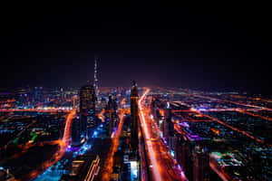 夜間杜拜城市景觀，摩天大樓燈火通明，道路閃爍發光。 — MacBook Pro 壁紙