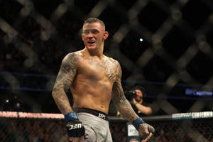 一位勝利的MMA拳手在八角籠內慶祝，紋身清晰可見。