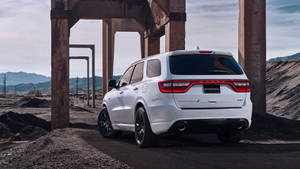 白色Dodge Durango SUV停泊在生鏽的鋼樑下，採石場背景有山脈。 — 汽車 壁紙