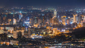 夜晚密集燈光的城市天際線景觀，高聳的建築物和發光的街道。 — 唐人街 GIF 壁紙