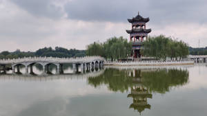 陰天下平靜水面倒映的中式亭閣和石橋 — 湖景 壁紙