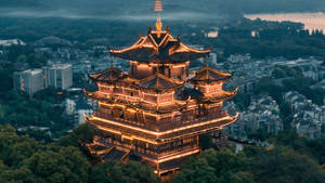 燈火通明的中式寶塔在暮色中於城市景觀上方閃耀。 — 湖景 壁紙