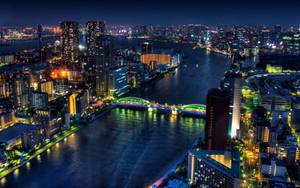 夜晚的城市，發光的建築物和水上亮燈的橋樑。 — 日式波浪 壁紙