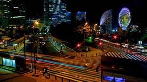 夜間城市景觀，發光的建築物和摩天輪，汽車燈光軌跡。
