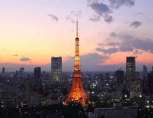 黃昏時分亮燈的東京塔，背景中城市燈光閃爍。 — 東京 壁紙