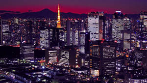 黃昏時分的東京城市燈光，背景是富士山。