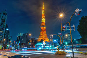 夜晚的東京塔亮起燈光，前景有車燈的軌跡。 — 東京 壁紙
