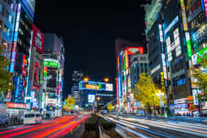 東京夜晚一條閃爍霓虹燈的街道，帶有行駛車輛的光跡。 — 東京 壁紙